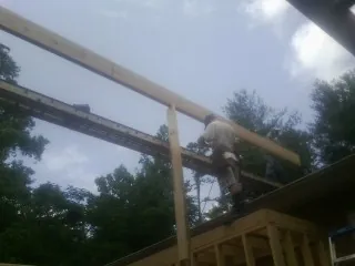 Carpenter setting a ridge beam over a new addition frame — Ice Dam Removal by Roofing Brothers in Sanbornton