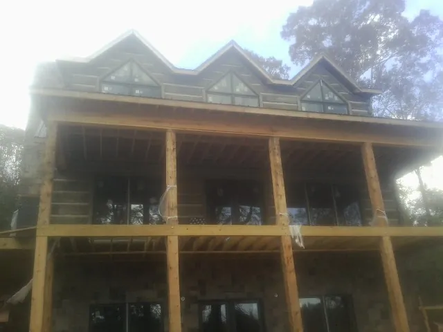 Dormers and porch framing on a large log home under construction — Roof Coating work by our crew in Sanbornton