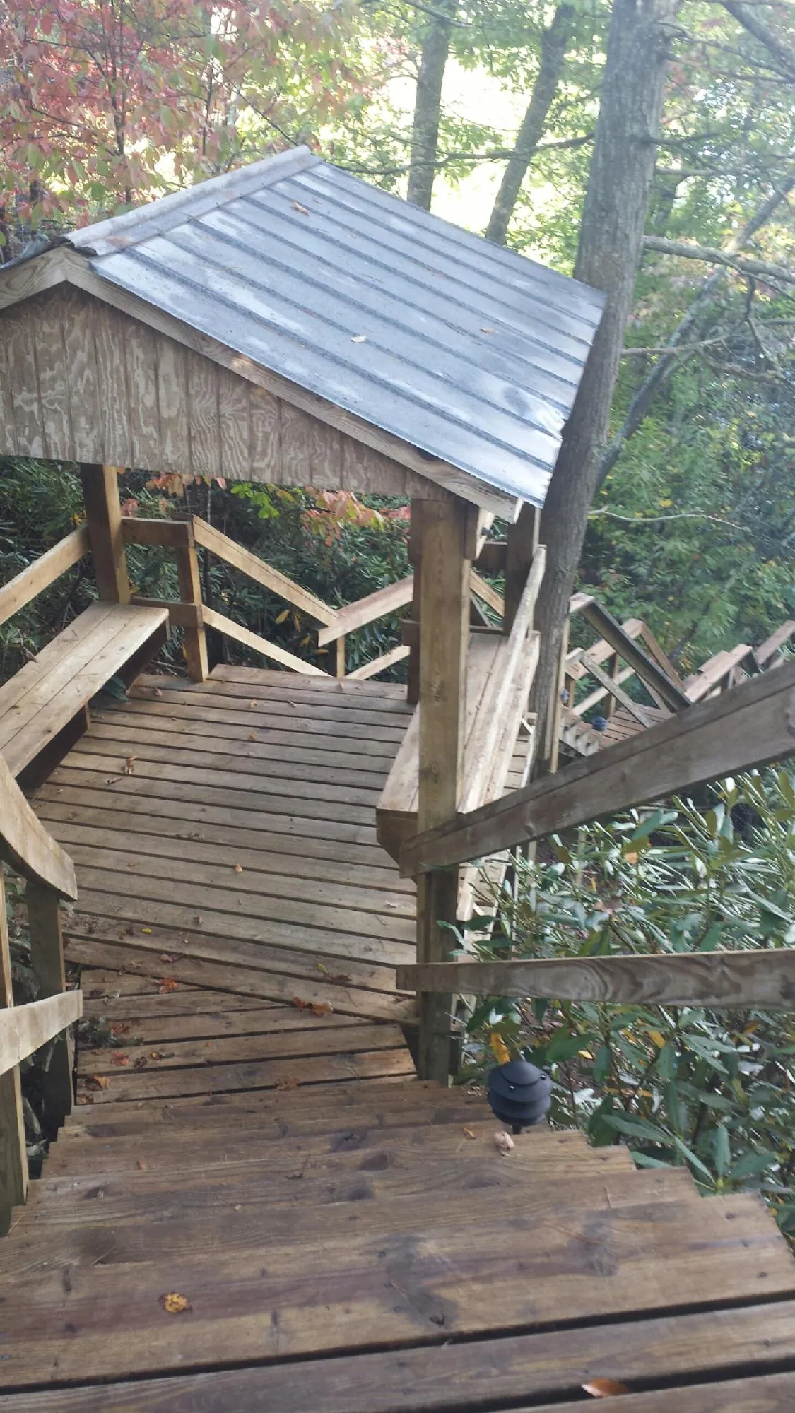 Metal roofed shelter over wooden steps on a wooded walkway — Skylight Repair & Installation work by our crew in Sanbornton