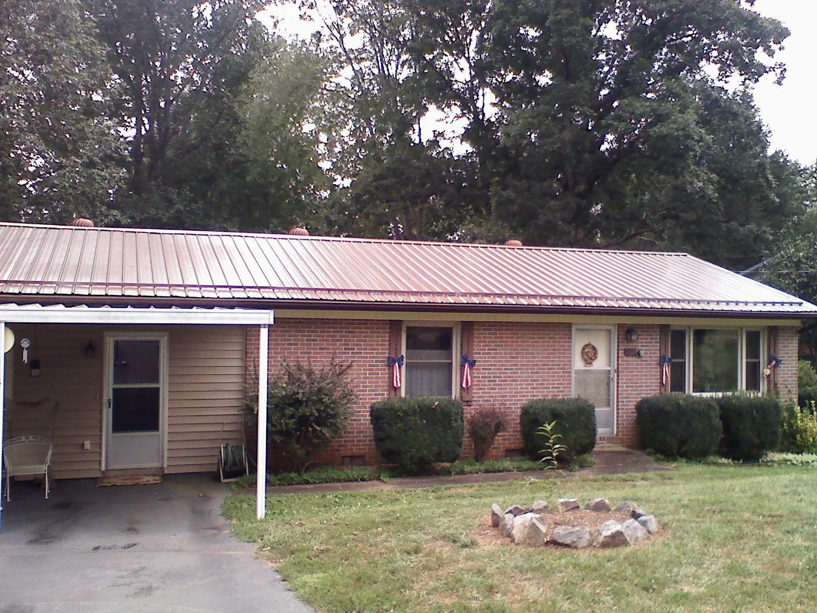 Bronze metal roof and carport on a brick ranch home — Roof Repair work by our crew in Sanbornton